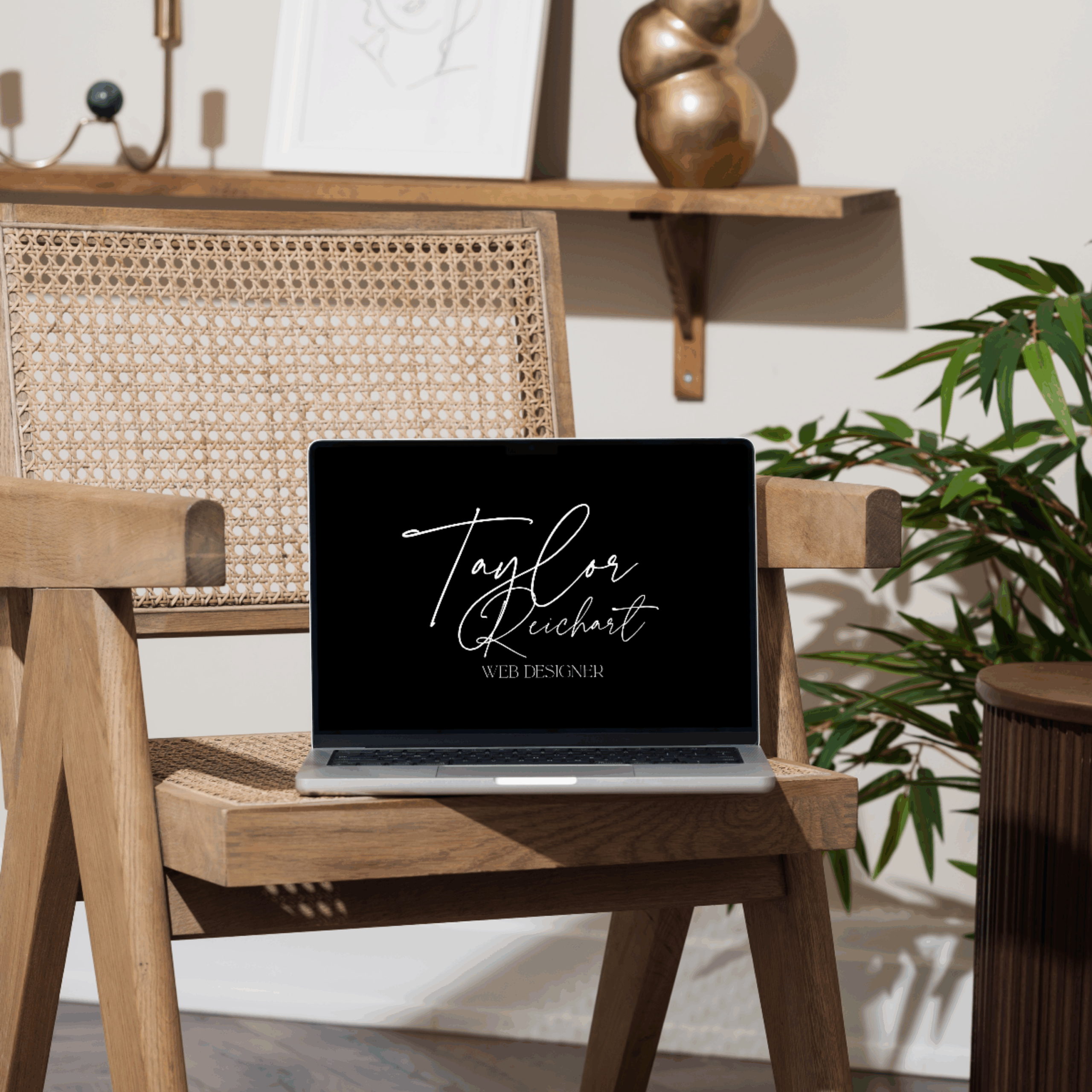 Minimal laptop setup in a chair with “Taylor Reichart, Web Designer” visible on the screen, reflecting a clean, modern web design workspace.